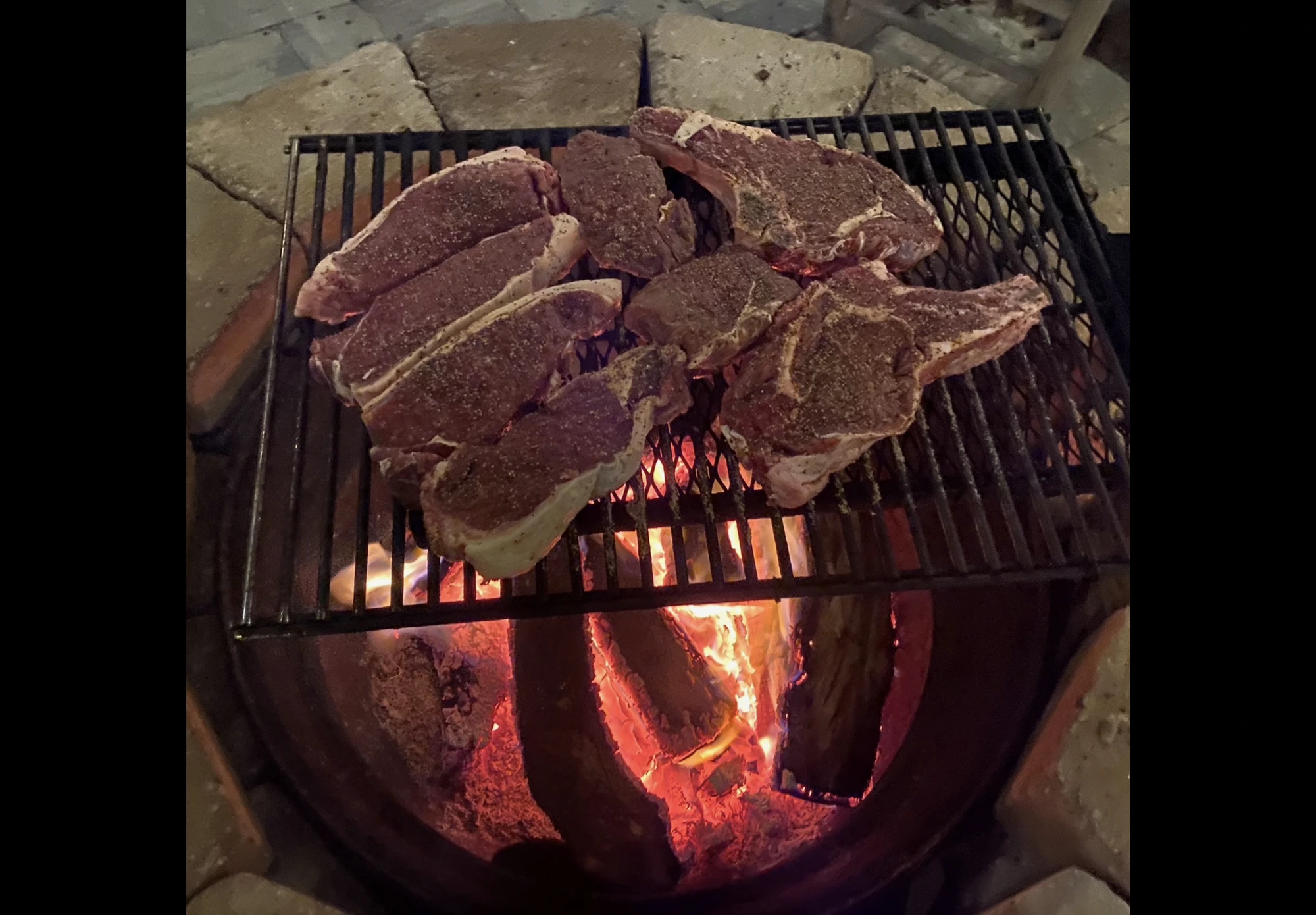 Steaks cooking over an open wood fire